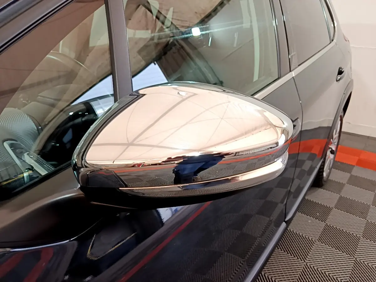 Rétroviseur chromé en gros plan côté gauche d'un Peugeot 2008 gris foncé, vue partielle du véhicule stationné.