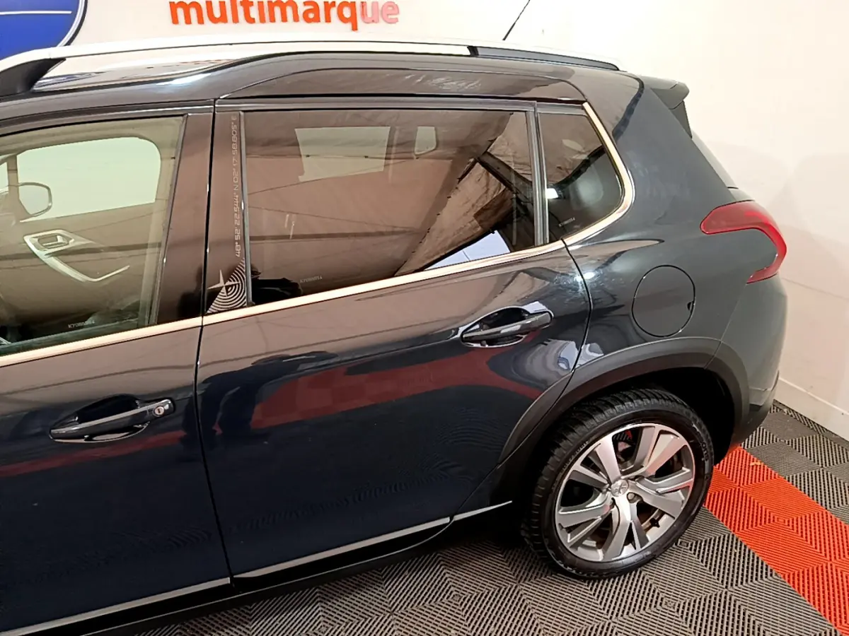 Vue latérale côté droit du Peugeot 2008 gris foncé avec poignées de porte et jante arrière visibles.