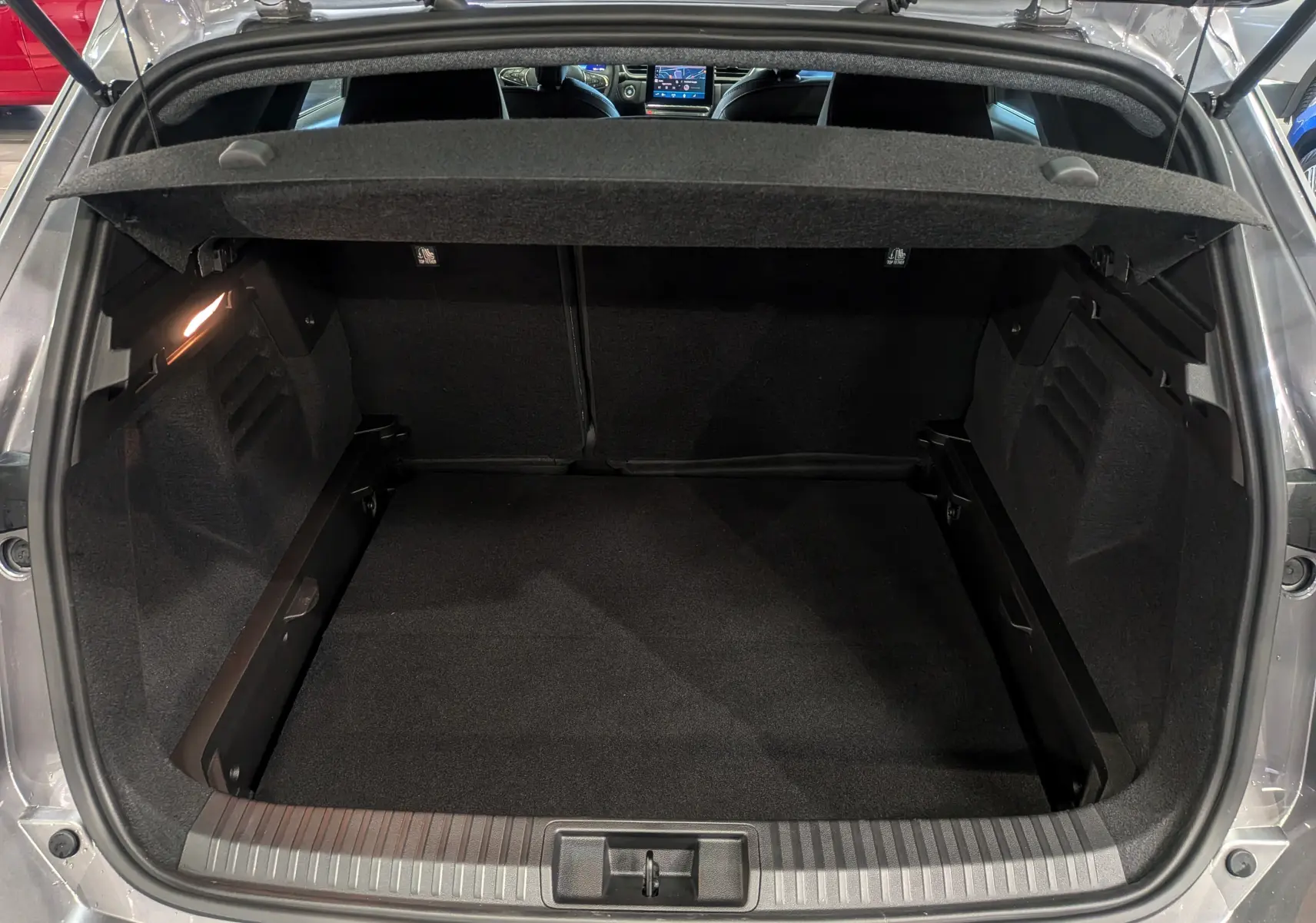 Coffre ouvert vu de l'arrière du Renault Symbioz gris Cassiopé, montrant un espace de chargement propre et spacieux.