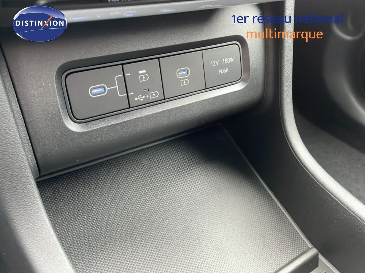 Détail de la console centrale du Hyundai Tucson 2026 montrant les ports USB et prise 12V dans un intérieur noir.