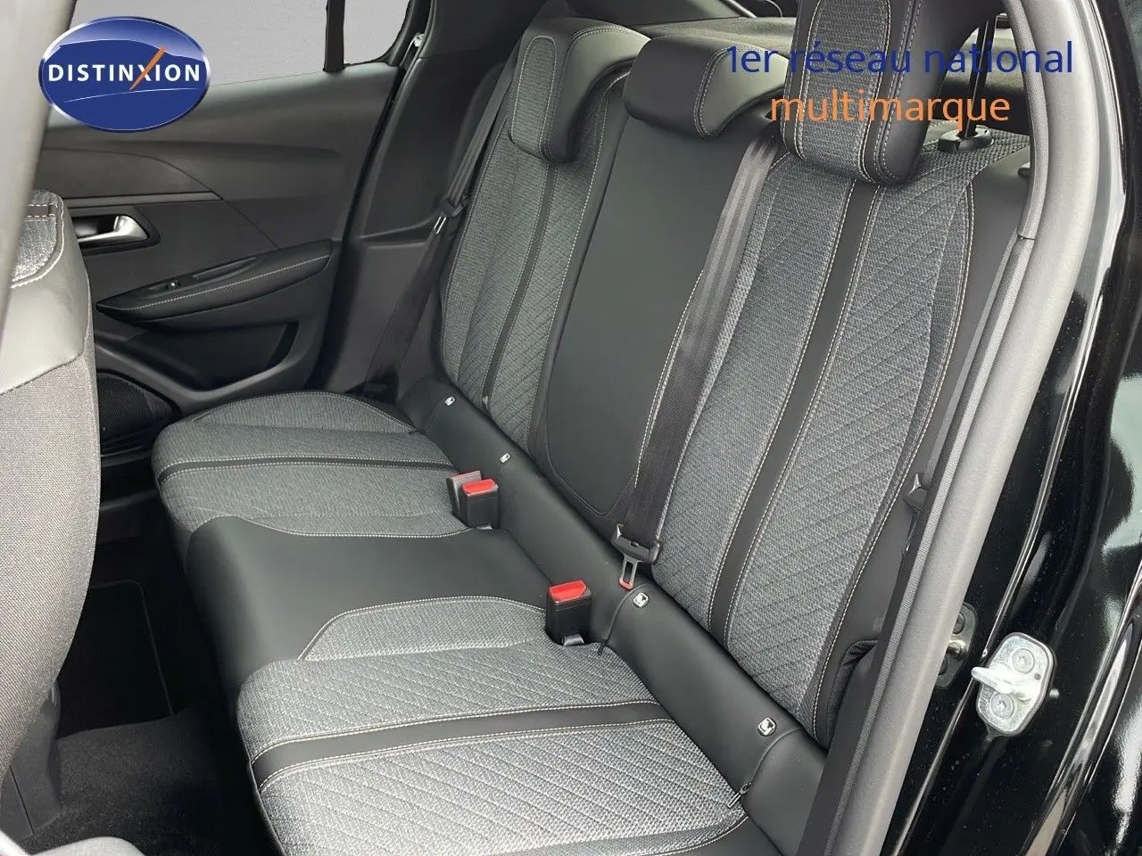 Vue latérale droite de l'arrière d'une Peugeot 208 noire avec sièges arrière en tissu gris et cuir noir.