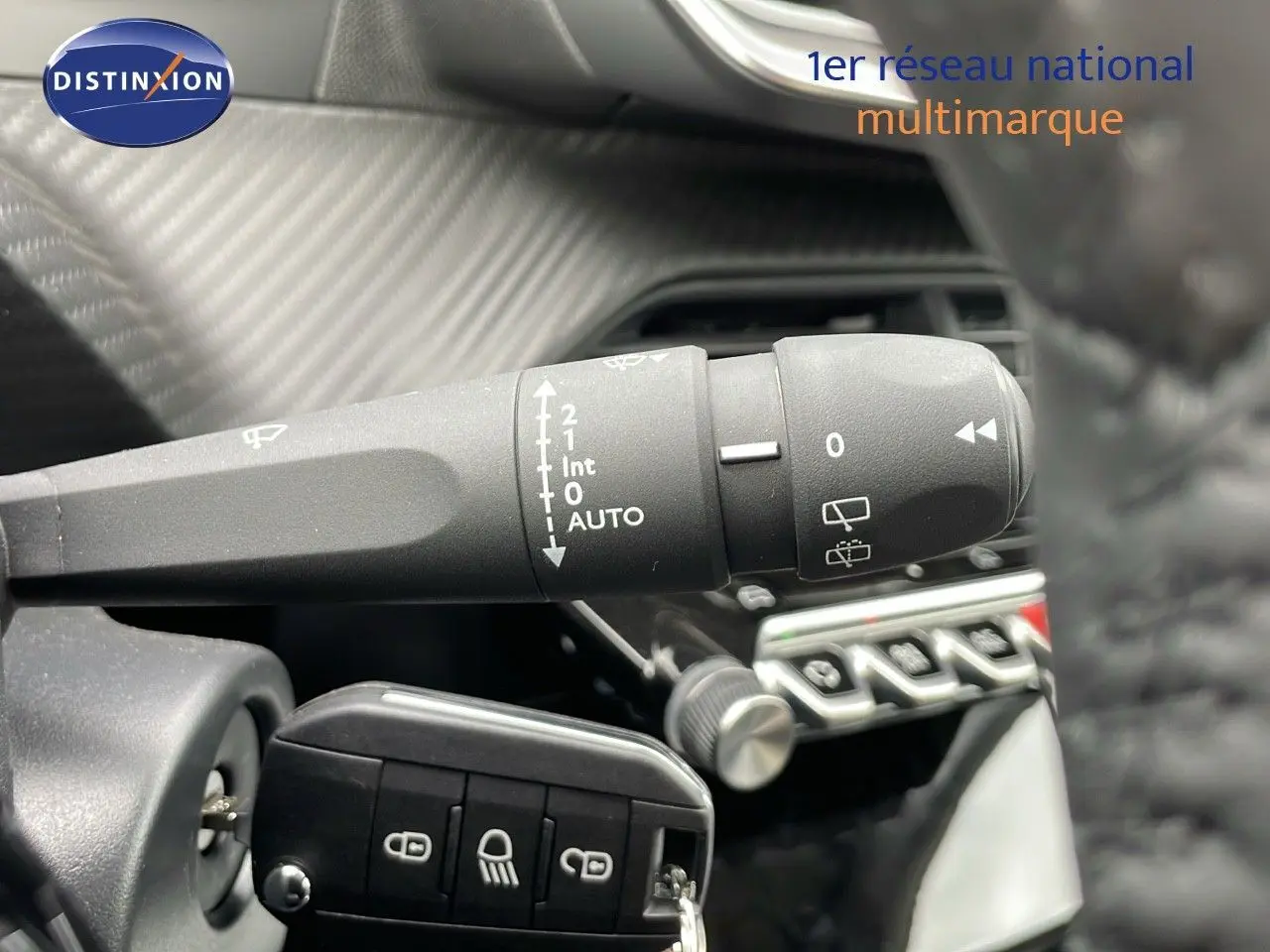 Gros plan sur la commande d'essuie-glace et la clé de contact dans l'habitacle d'une Peugeot 208 noire.