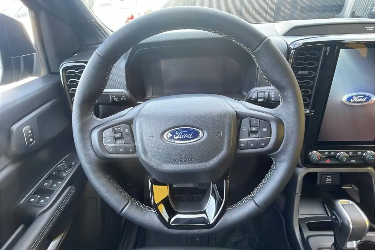 Vue centrée sur le volant cuir multifonctions du Ford Ranger 2025, avec écran tactile et commandes au volant visibles.