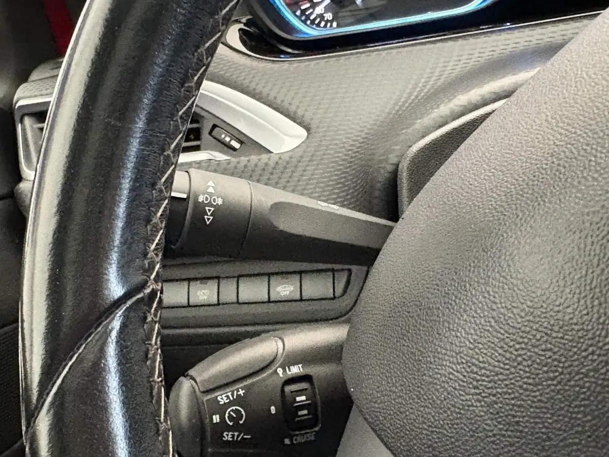 Gros plan sur le volant cuir et commandes de régulateur de vitesse du Peugeot 2008 rouge Puretech 2019