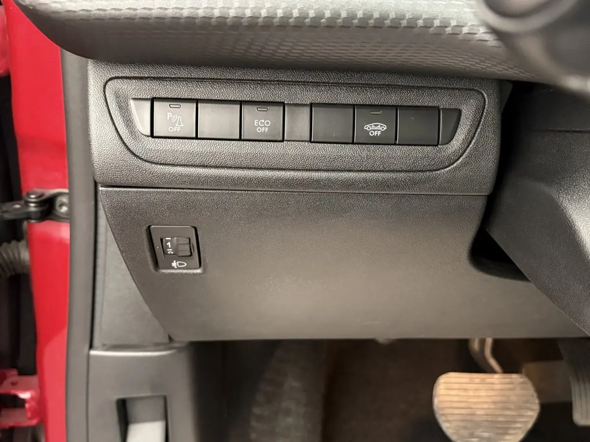 Détail intérieur côté gauche du tableau de bord noir avec boutons de contrôle et portière rouge visible Peugeot 2008 2019.