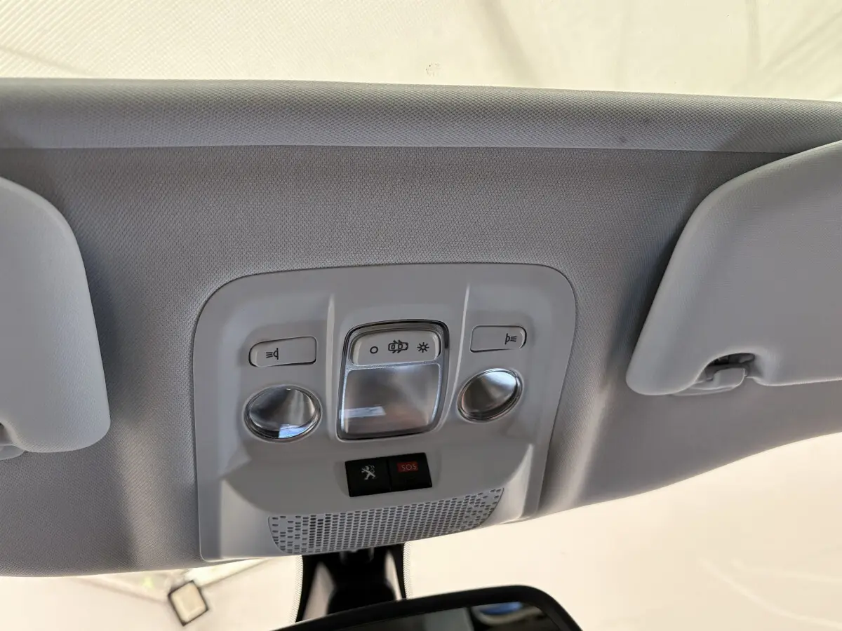 Plafonnier intérieur gris clair avec commandes d'éclairage et bouton SOS dans un Peugeot 2008 rouge, vue de dessous