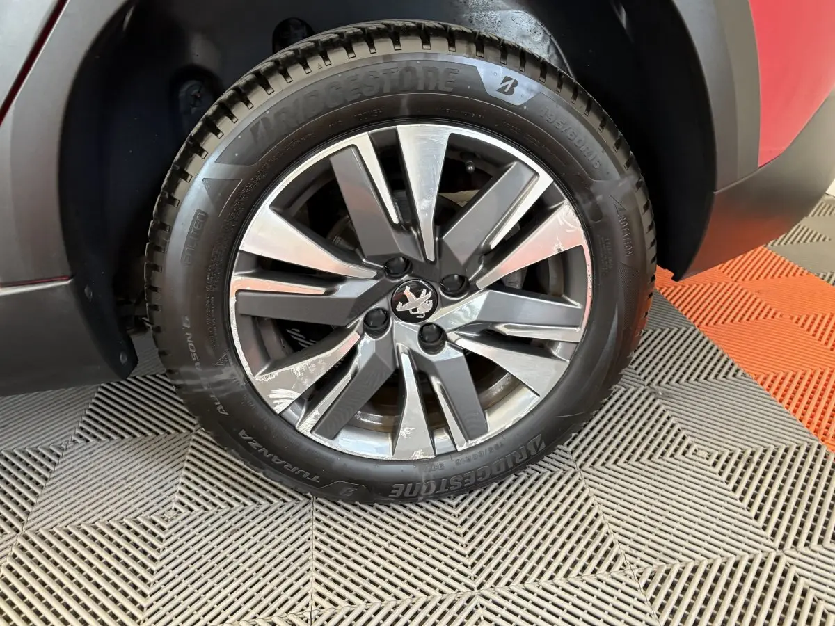 Gros plan sur la roue avant gauche du Peugeot 2008 rouge, avec jante alliage et pneu Bridgestone.