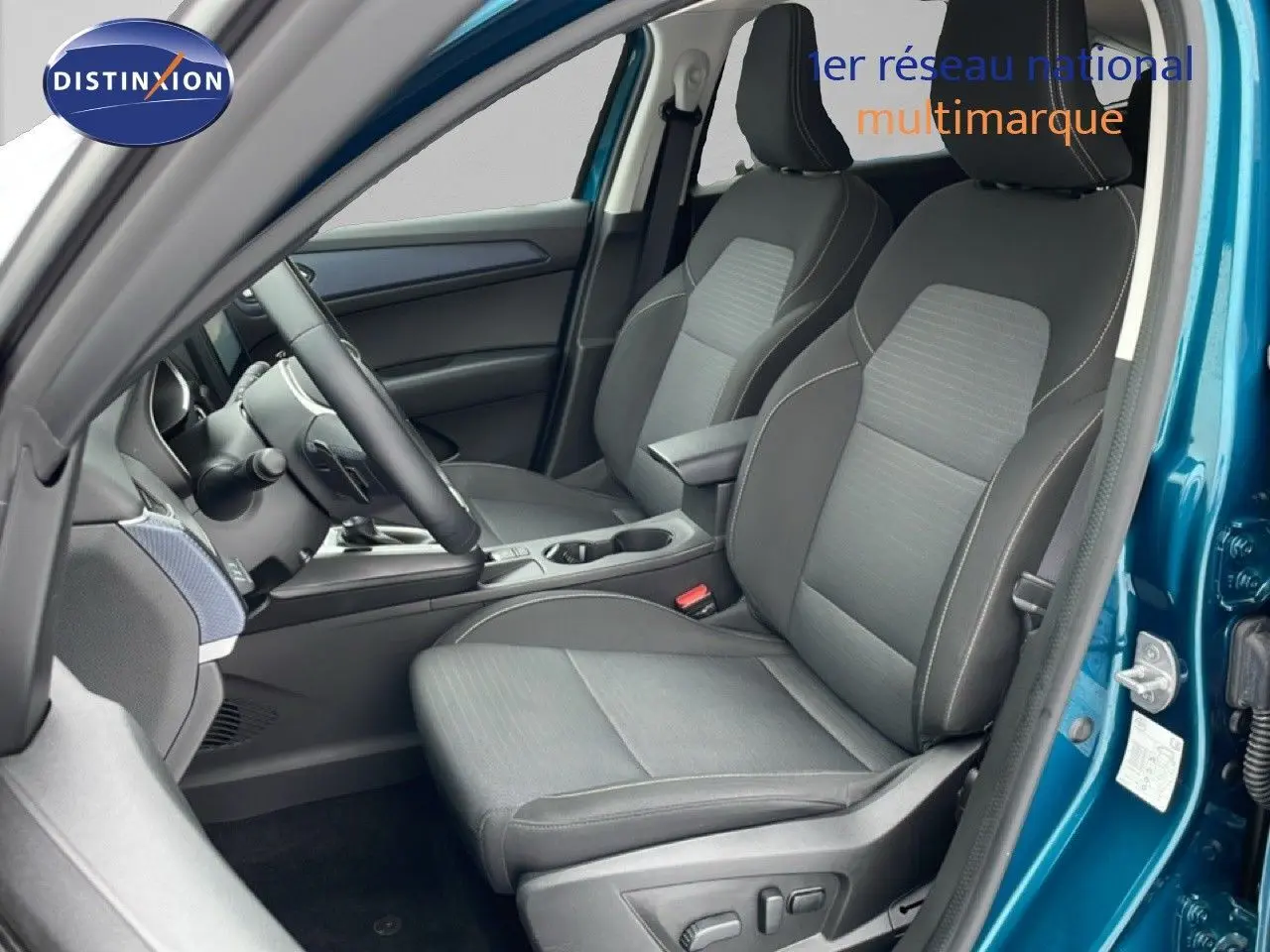 Vue intérieure côté conducteur du Renault Arkana bleu Zanzibar, mettant en valeur les sièges en tissu noir et la console centrale.