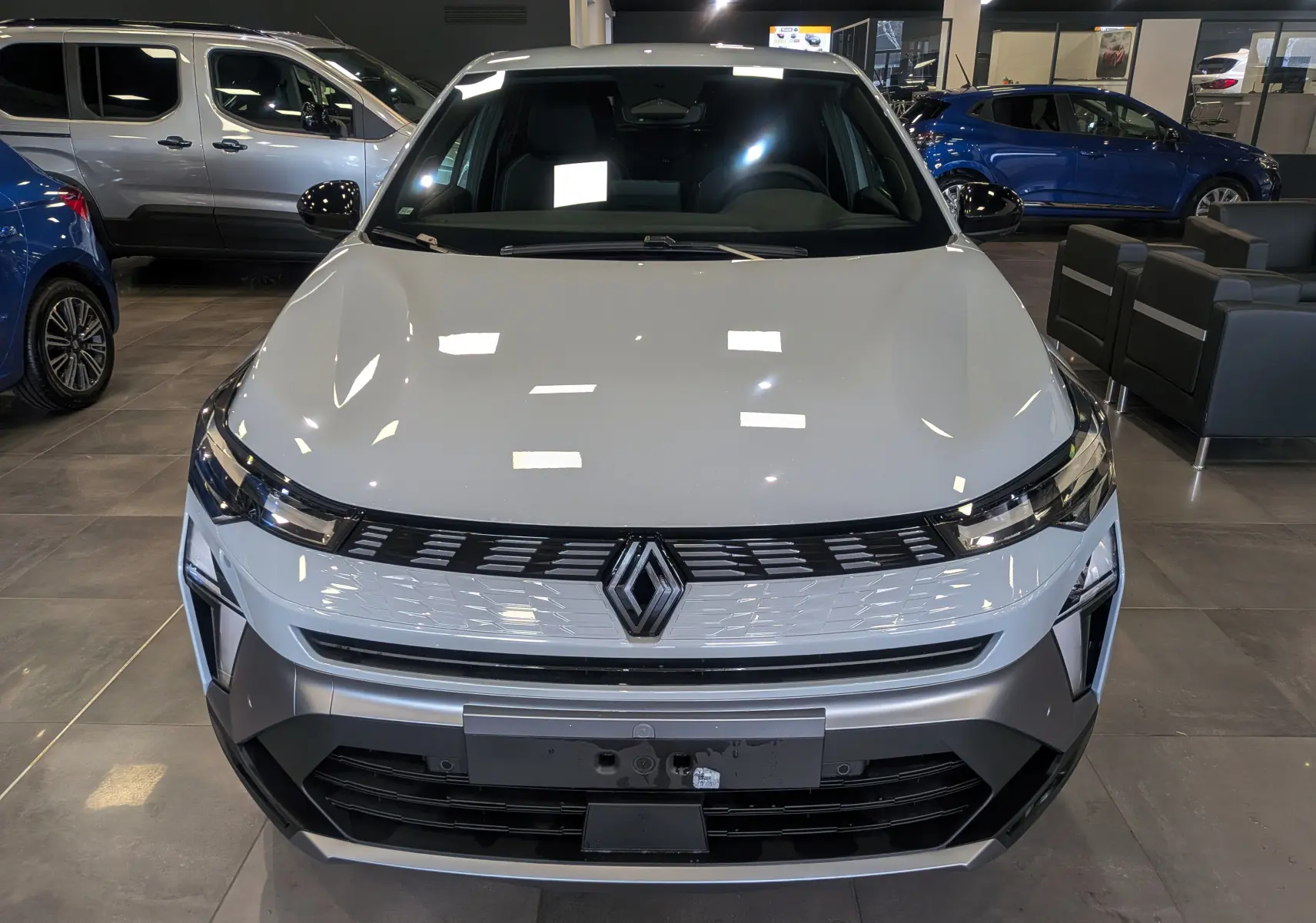 Vue avant d'une Renault SYMBIOZ E-TECH Full Hybrid gris Rafale, avec calandre moderne et logo Renault central lumineux.