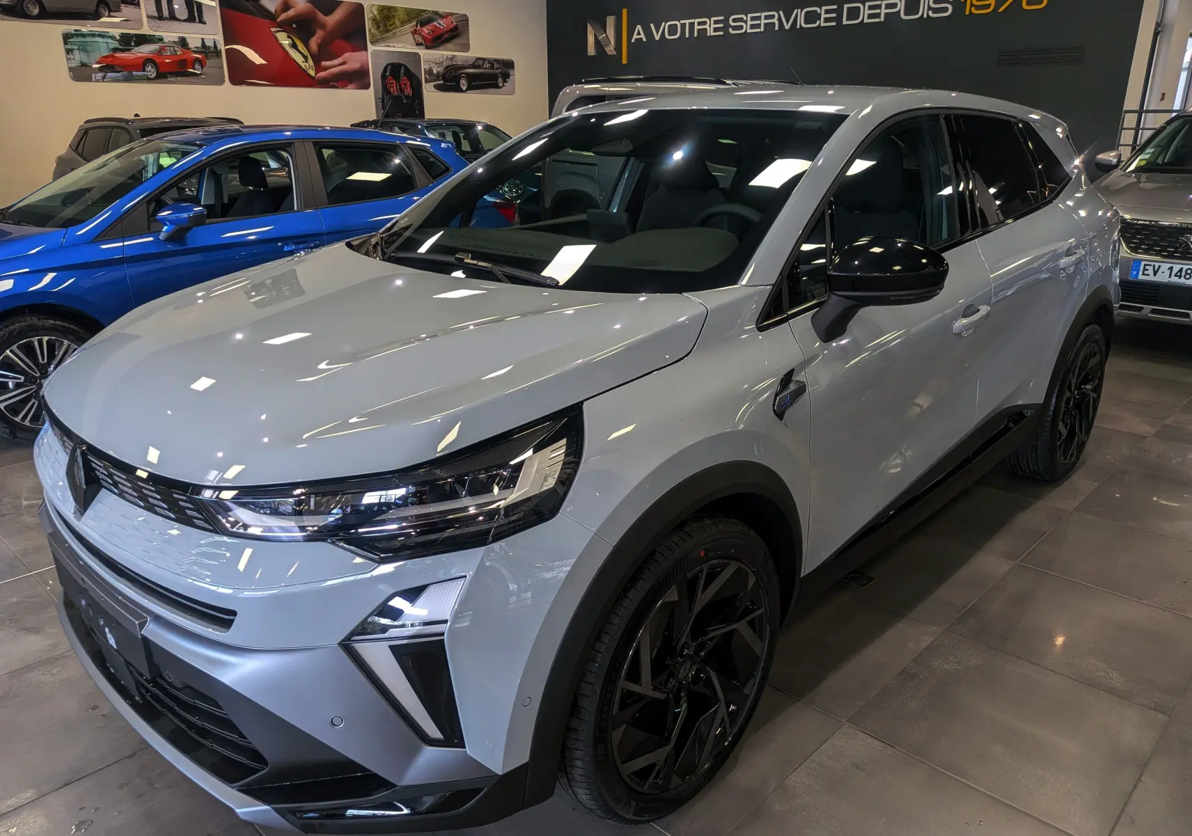 Renault Symbioz E-Tech gris Rafale en 3/4 avant droit, avec jantes noires et rétroviseurs noirs brillants.