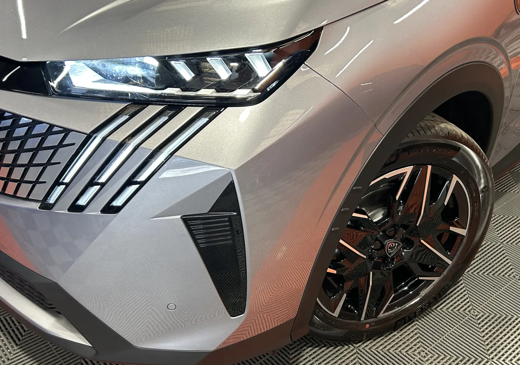 Gros plan sur l’avant droit gris Artense du Peugeot 3008 Hybrid avec phares LED et jante alliage noire brillante.