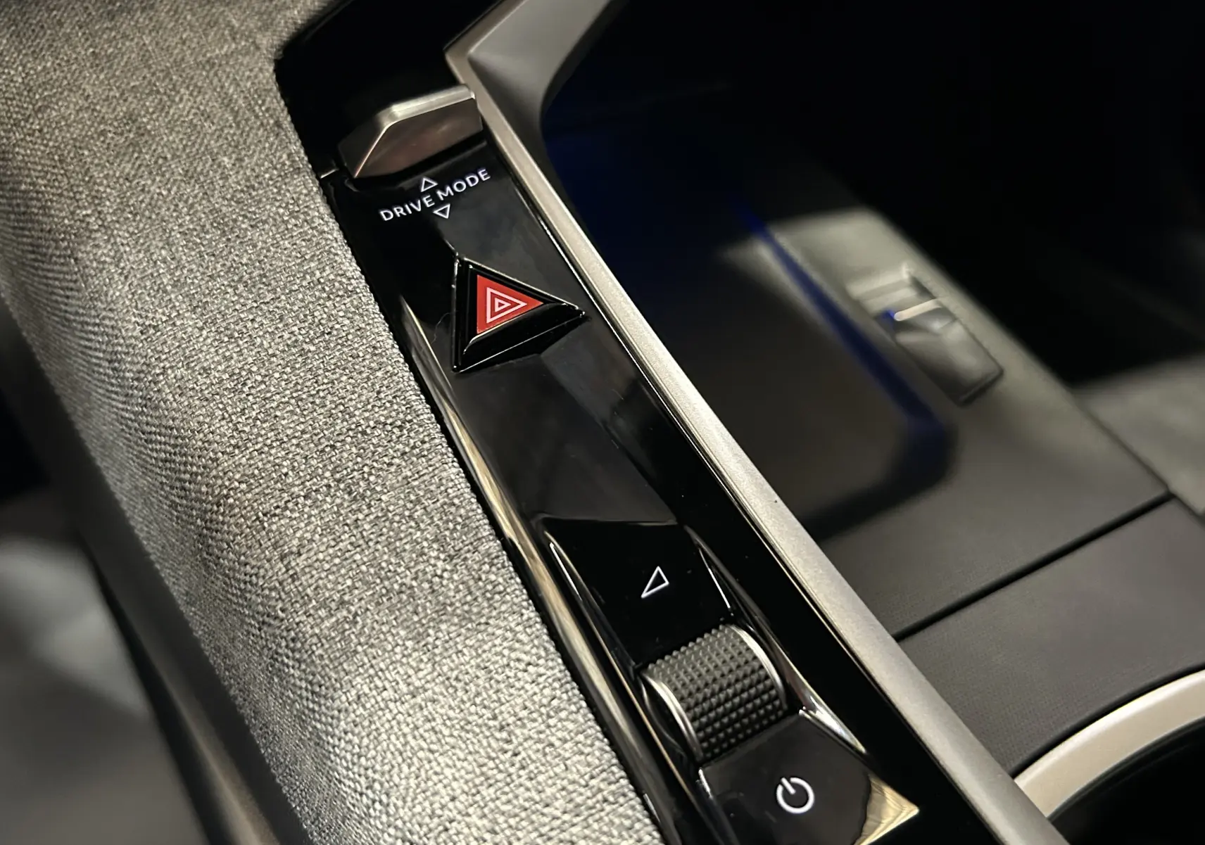 Gros plan sur la console centrale noire et grise du Peugeot 3008 Hybrid avec bouton triangle rouge d’alerte et molette Drive Mode.