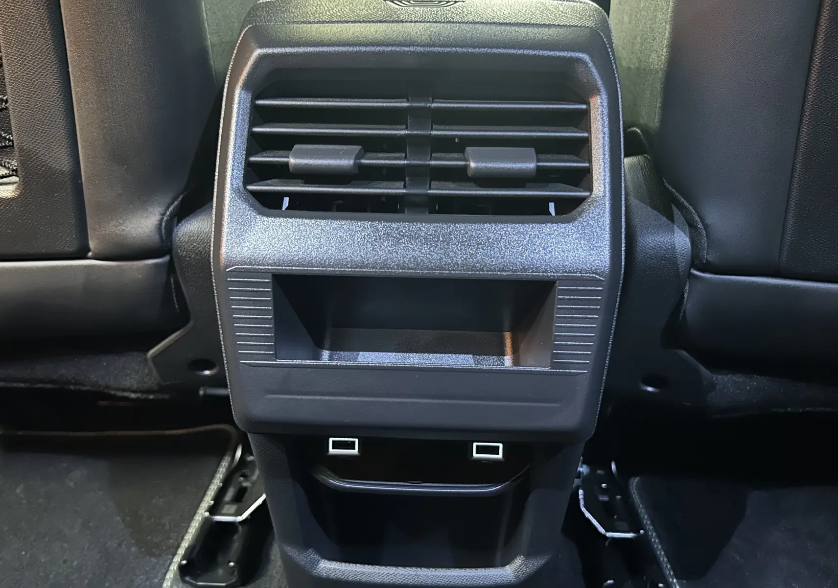 Vue rapprochée de la console arrière noire avec bouches d’aération et ports USB du Peugeot 3008 gris Artense.
