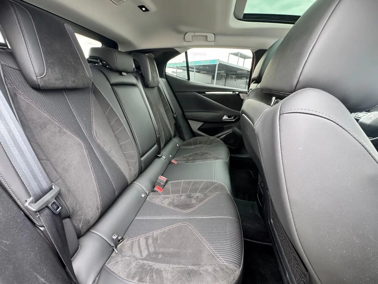 Vue intérieure arrière du DS4 2022 avec sièges en cuir et Alcantara noir, toit ouvrant panoramique visible.