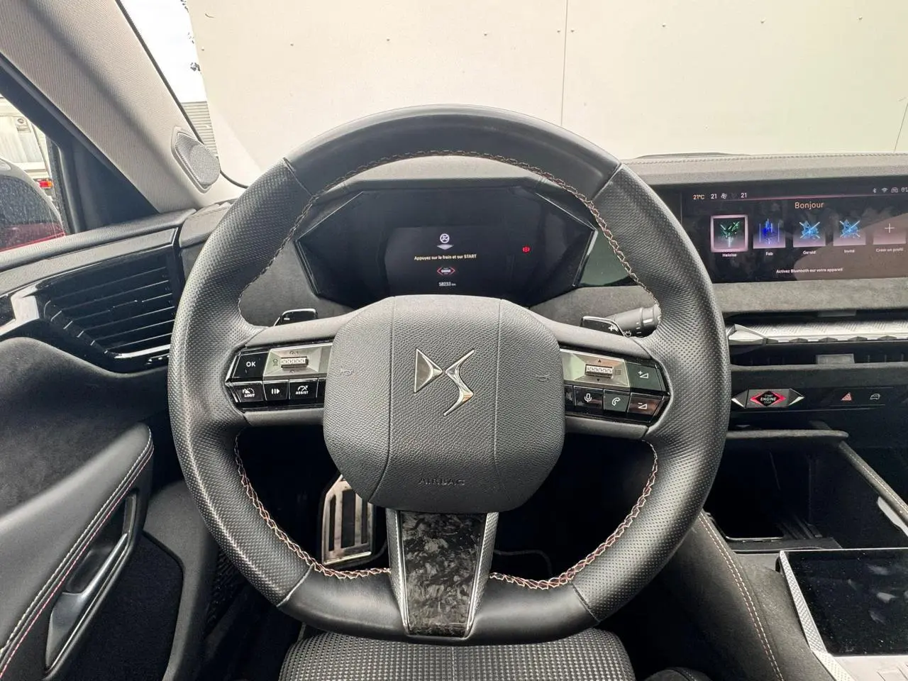 Vue rapprochée du volant en cuir noir avec surpiqûres rouges et tableau de bord numérique du DS4 Performance Line 2022.