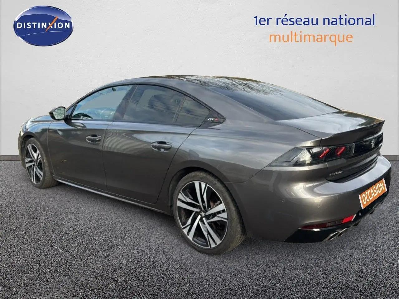 Vue 3/4 arrière droite d'une Peugeot 508 gris platinium, avec jantes bi-ton et feux arrière caractéristiques GT Line.