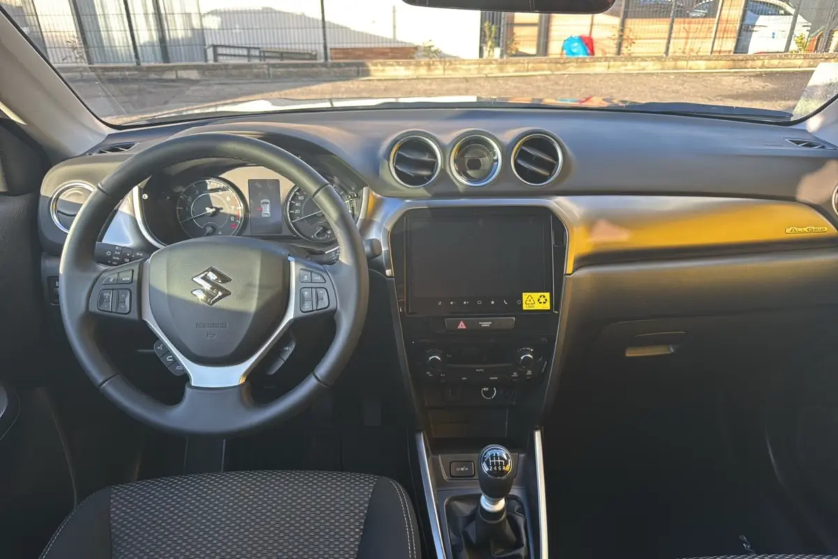 Vue intérieure frontale du tableau de bord et volant cuir multifonctions du Suzuki Vitara Hybrid 2025 avec écran tactile 9 pouces.