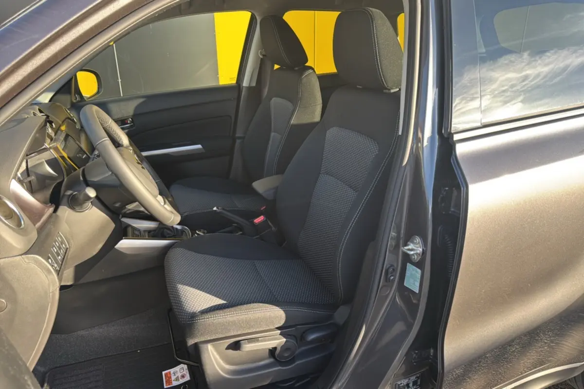 Intérieur avant droit du Suzuki Vitara Hybrid 110 Privilege AllGrip 2025 en Titan dark gray, sièges tissu gris et volant cuir.
