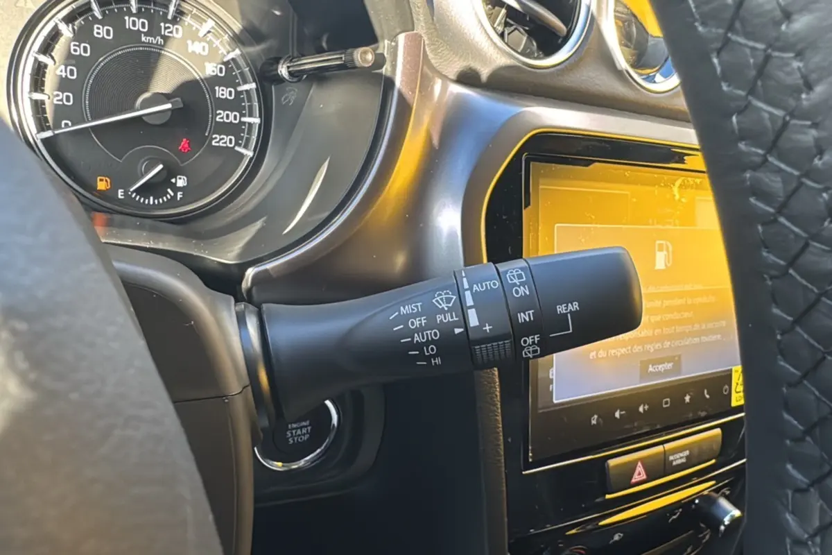 Gros plan sur la commande d’essuie-glace et le tableau de bord noir du Suzuki Vitara Hybrid 2025, écran tactile allumé.