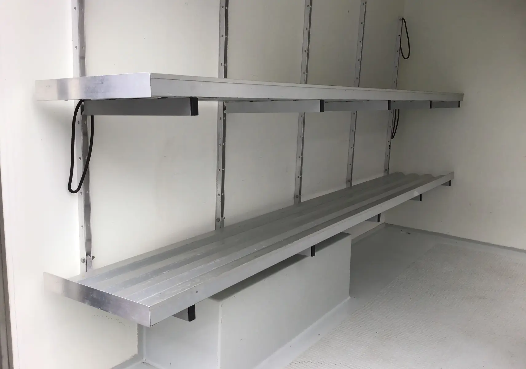 Intérieur de la caisse frigorifique blanche du Renault Trafic Planche cabine, montrant les étagères métalliques sur le côté gauche.