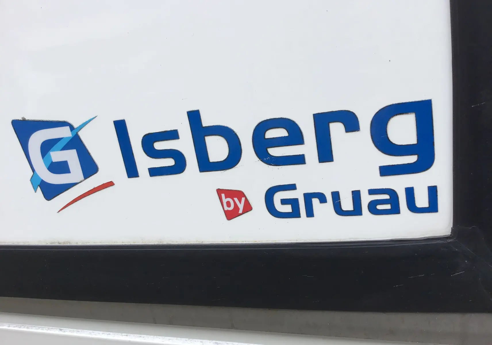 Gros plan sur le logo bleu Isberg by Gruau sur la caisse frigorifique blanche du Renault Trafic Plancher Cabine.