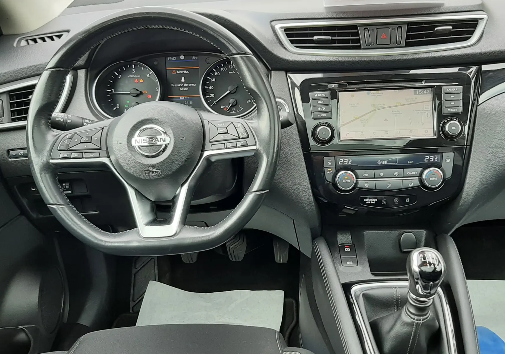 Vue intérieure du tableau de bord et volant noir du Nissan Qashqai blanc 2020 avec boîte manuelle et écran tactile central.
