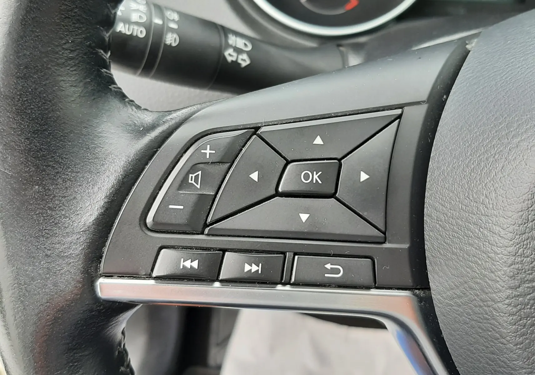 Gros plan sur les commandes au volant côté gauche du Nissan Qashqai blanc 2020, avec tableau de bord en arrière-plan.