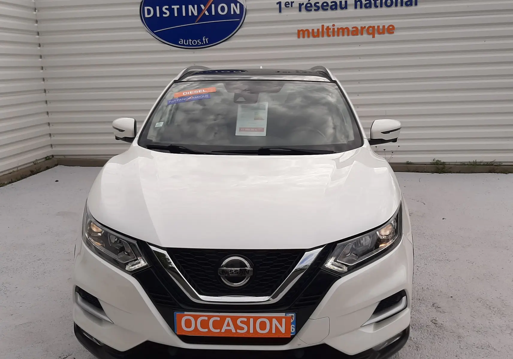 Vue frontale d'un Nissan Qashqai blanc 2020 avec plaque "OCCASION" et logo Nissan bien visible sur la calandre.