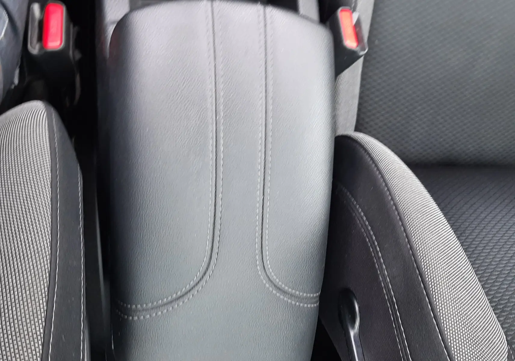 Gros plan sur l'accoudoir central en cuir noir et les sièges tissu gris du Nissan Qashqai 1.5 DCI blanc de 2020.