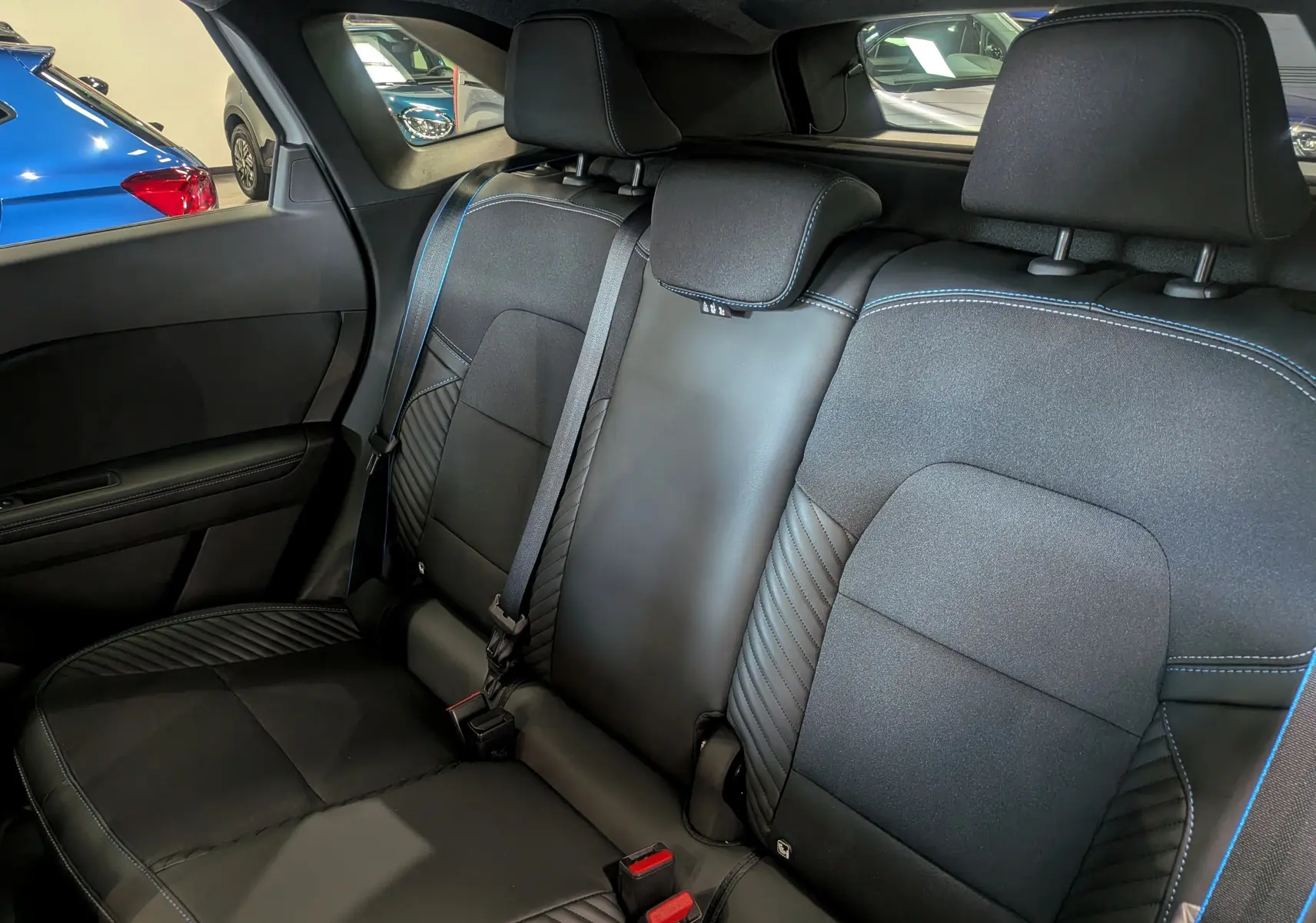 Vue intérieure arrière droite des sièges noirs en cuir et tissu avec surpiqûres bleues du Renault Symbioz E-TECH 2026.