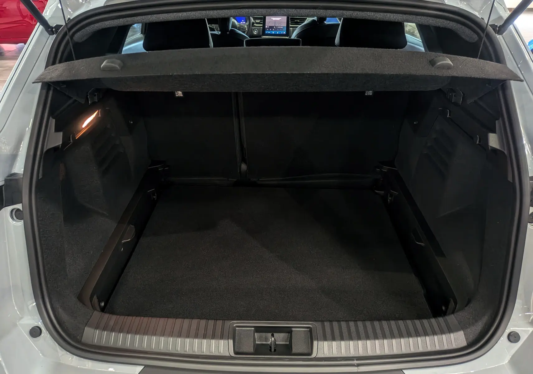 Coffre ouvert vu de l'arrière d'une Renault SYMBIOZ gris Rafale, montrant un espace de chargement propre et spacieux.