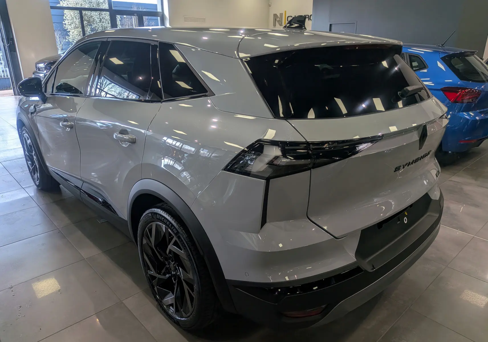 Vue 3/4 arrière droite du Renault SYMBIOZ gris Rafale avec jantes noires et vitres teintées en showroom.
