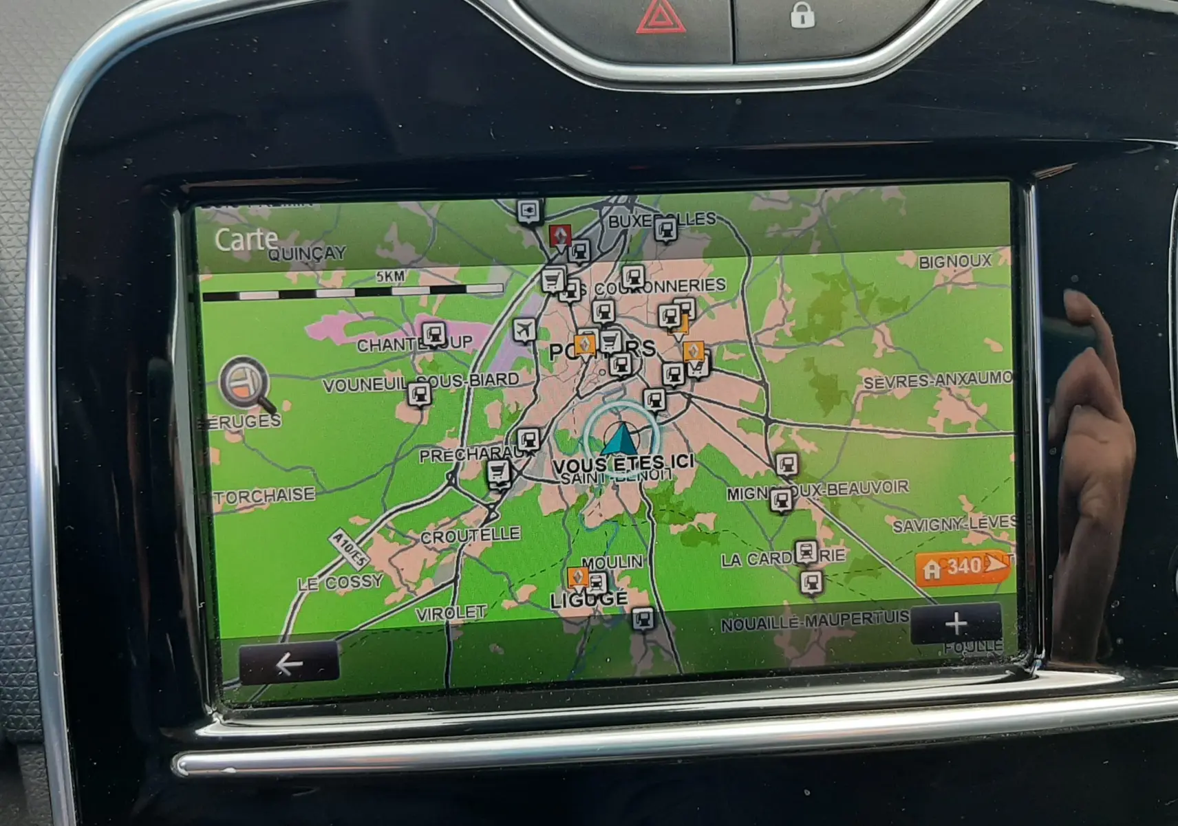 Écran tactile de navigation GPS affichant une carte, intégré dans le tableau de bord noir d'une Renault Clio IV beige.