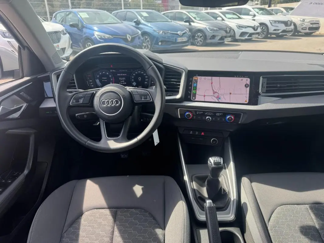 Vue intérieure avant de l'Audi A1 Sportback gris 2025, volant cuir, cockpit numérique et écran tactile avec navigation.