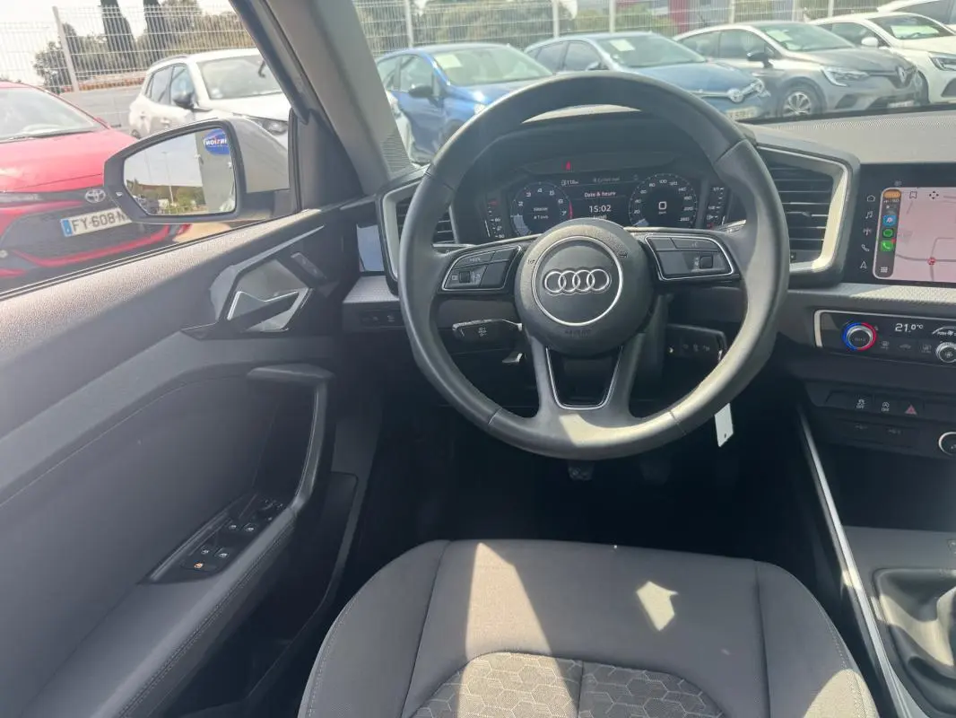Vue intérieure centrée sur le volant cuir et le cockpit numérique de l'Audi A1 Sportback 2025 en gris.