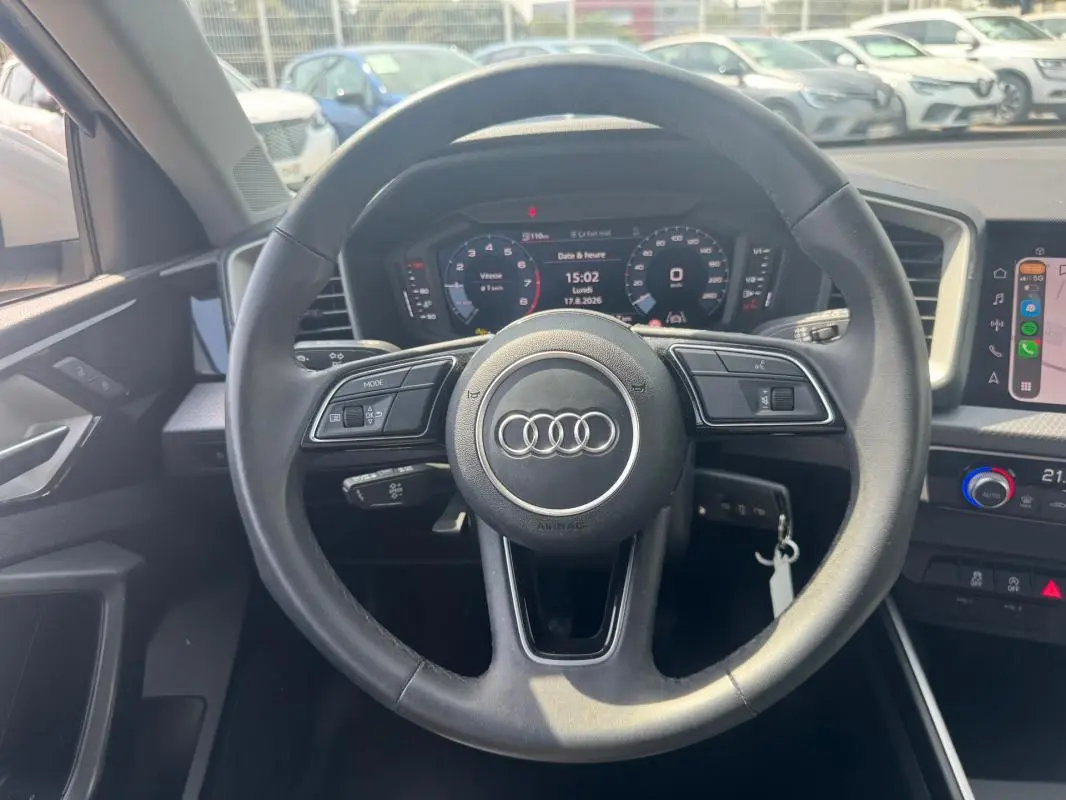 Vue intérieure centrée sur le volant cuir noir d’une Audi A1 Sportback 2025 avec cockpit numérique et console multimédia.