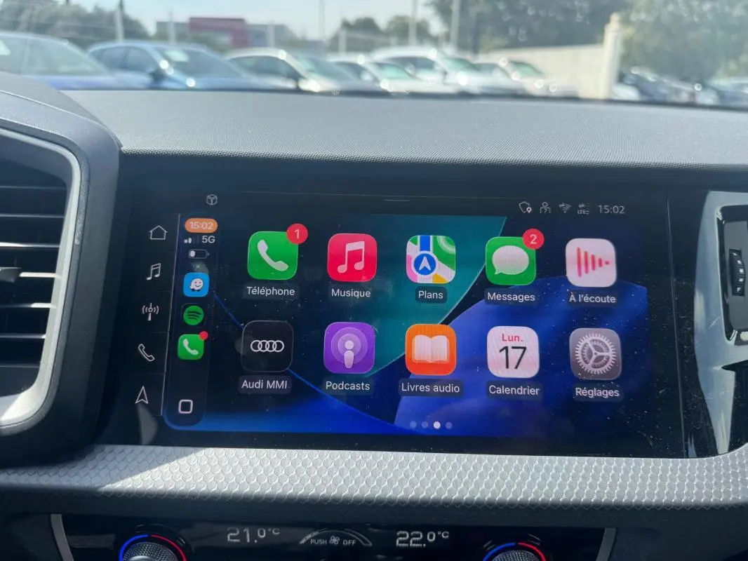Écran tactile central de l’Audi A1 Sportback 2025 affichant les applications multimédia, avec tableau de bord gris en arrière-plan.