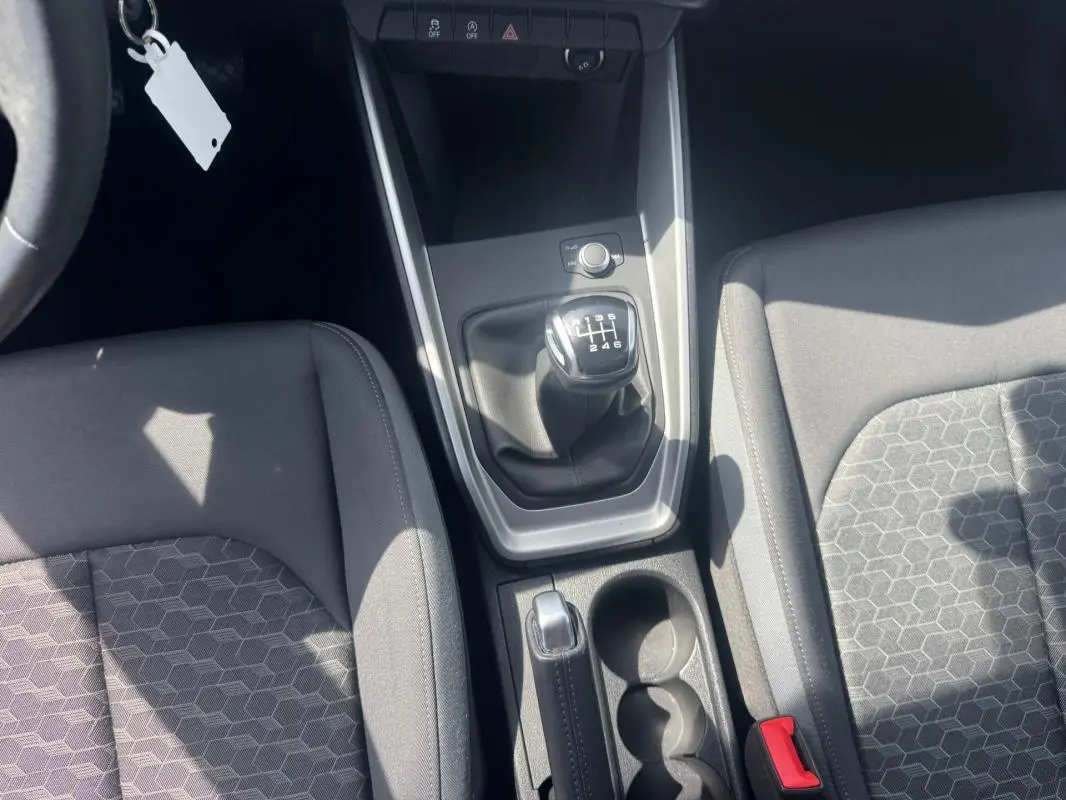 Vue intérieure centrée sur la console centrale d'une Audi A1 Sportback 2025 avec boîte manuelle et sièges sport gris.