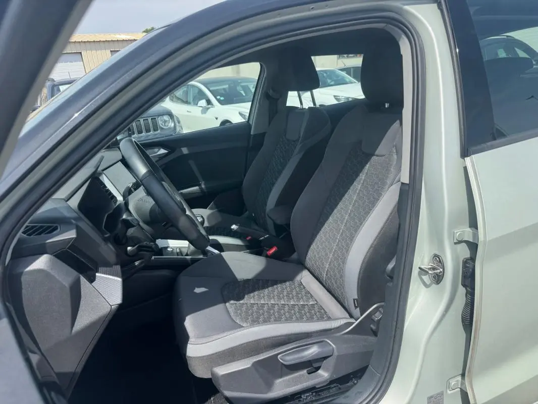 Vue intérieure côté conducteur de l'Audi A1 Sportback gris 2025, mettant en valeur les sièges sport et le volant cuir.