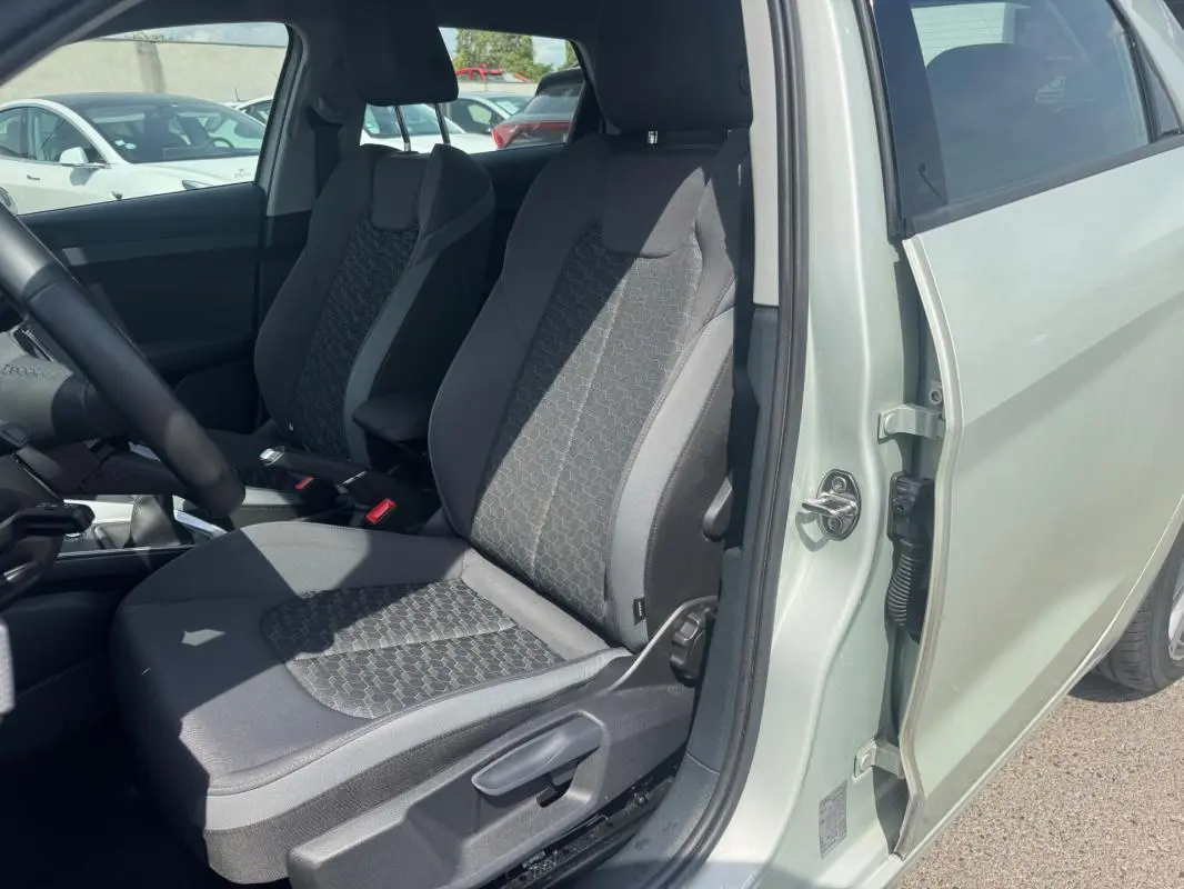 Vue intérieure côté conducteur de l'Audi A1 Sportback 2025 gris, mettant en valeur les sièges sport et l'accoudoir central.