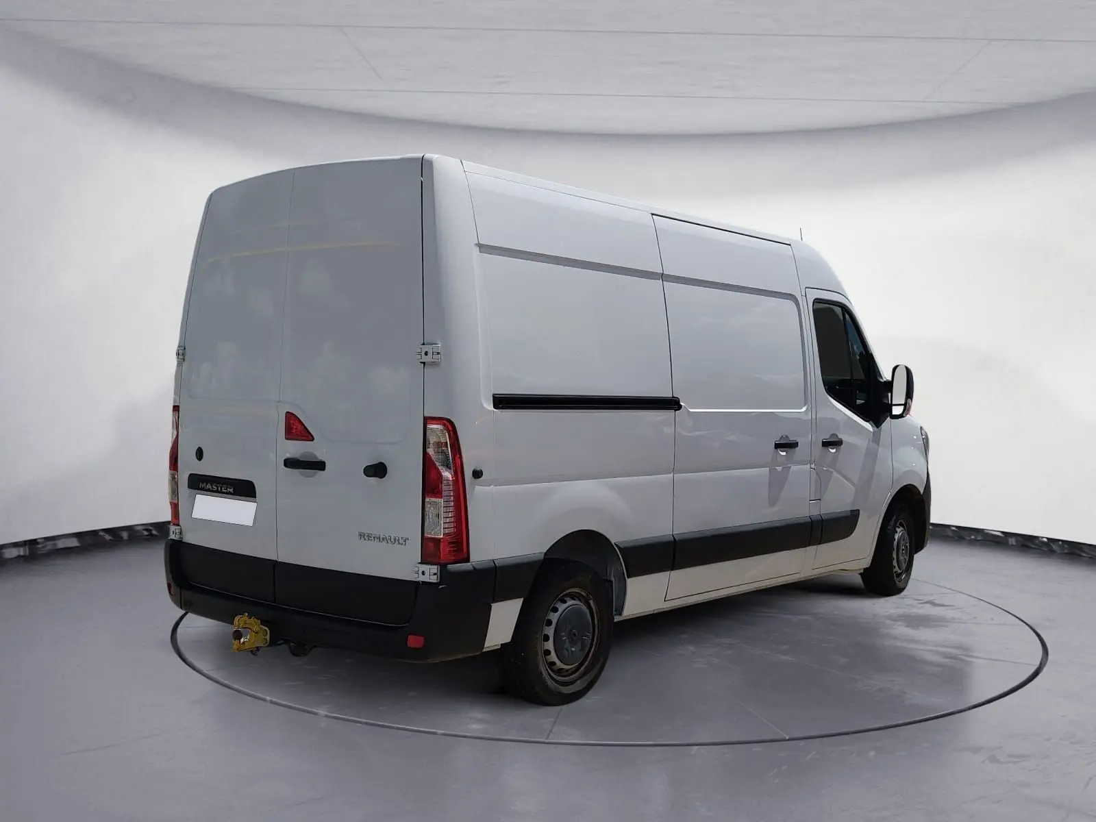 Vue 3/4 arrière droit d’un Renault Master blanc utilitaire avec hayon et attelage dans un studio gris.
