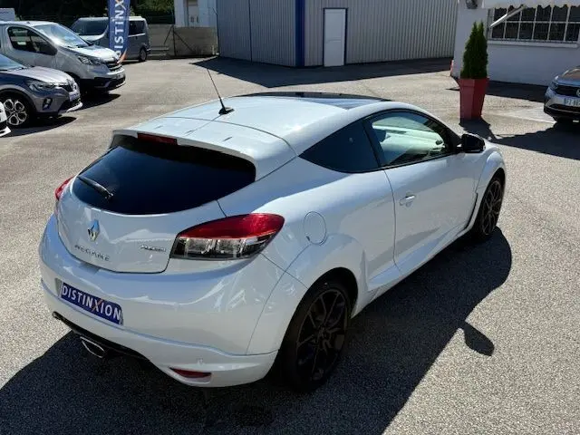Renault Mégane III Coupé 2.0T 265cv RS blanc nacré vue 3/4 arrière droit avec jantes noires et toit vitré.