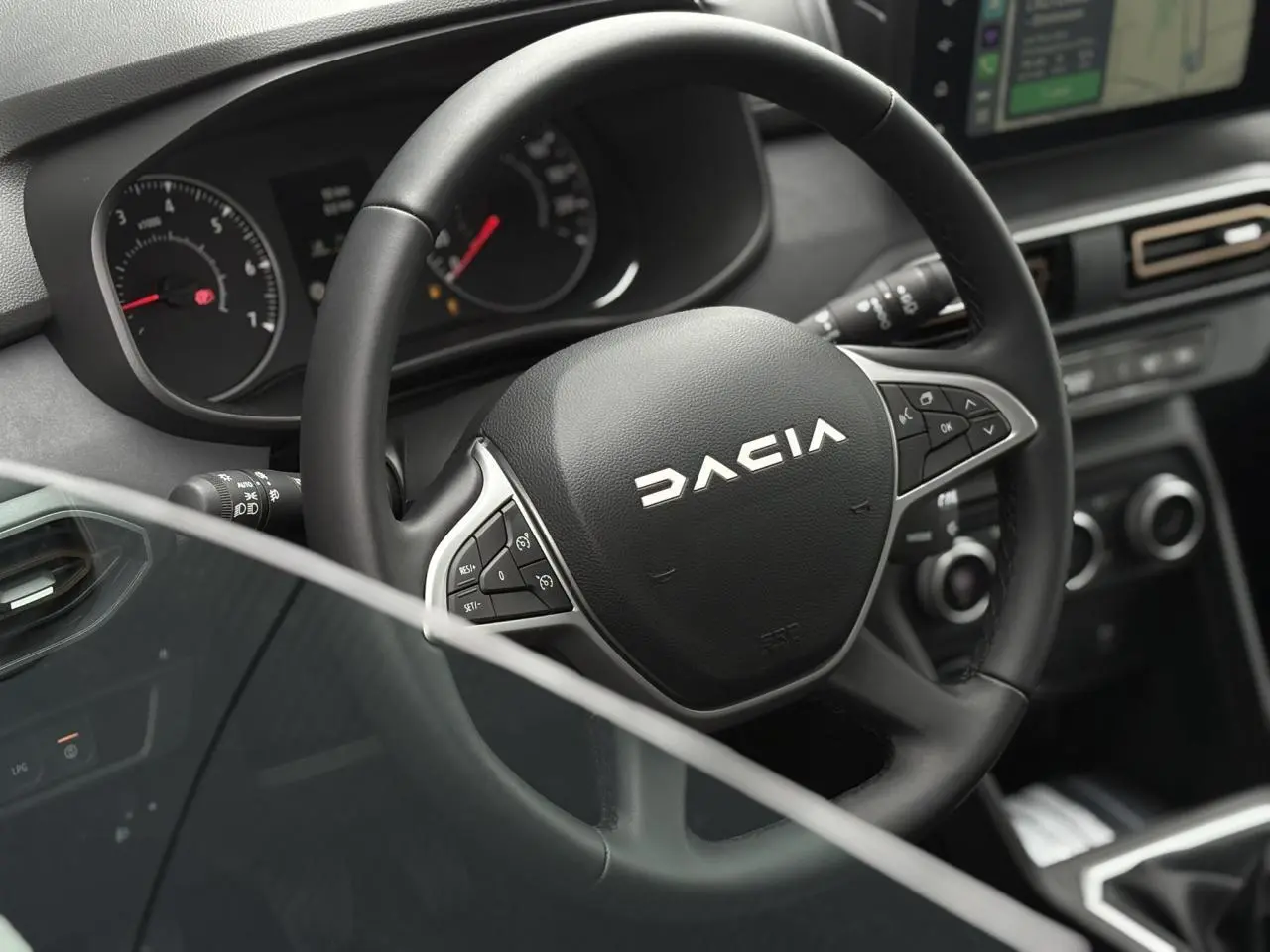 Vue rapprochée du volant noir de la Dacia Sandero Stepway 2025 avec commandes intégrées et tableau de bord numérique.