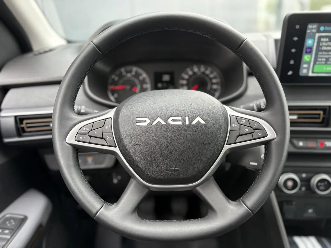 Vue rapprochée du volant noir Dacia avec commandes intégrées, tableau de bord et écran tactile du Sandero Stepway 2025.