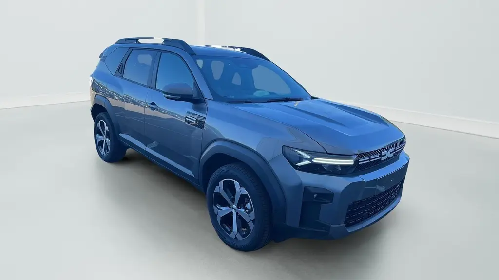 Vue 3/4 avant droite du Dacia Bigster 155 Journey gris schiste avec jantes alliage 18'' et barres de toit longitudinales.