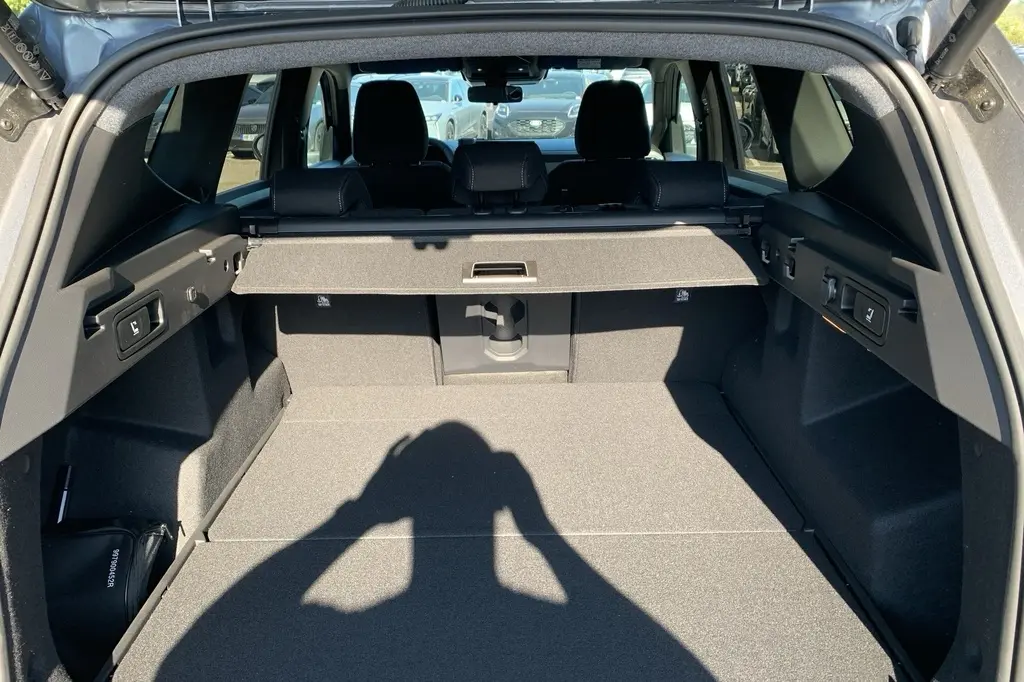 Vue intérieure du coffre ouvert du Dacia Bigster gris Schiste, montrant la tablette cache-bagages et les sièges arrière.