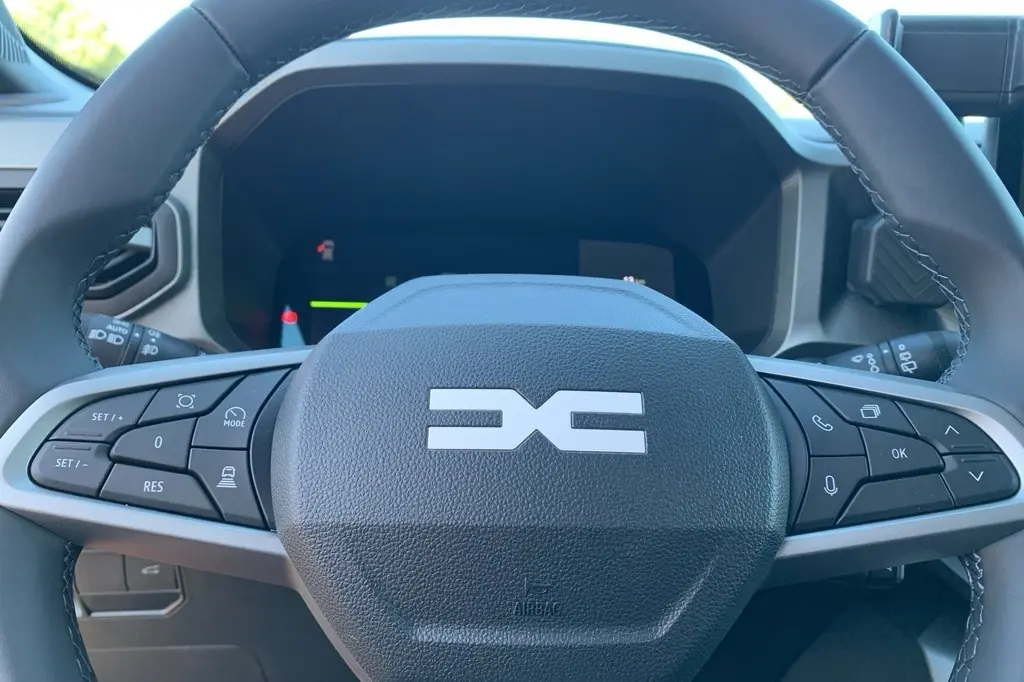 Gros plan sur le volant Soft Feel du Dacia Bigster 155 Journey avec commandes intégrées et logo central distinctif.