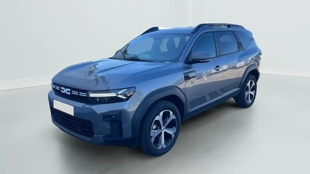 SUV Dacia Bigster 155 Journey gris schiste en 3/4 avant, avec jantes alliage 18'' et barres de toit longitudinales.