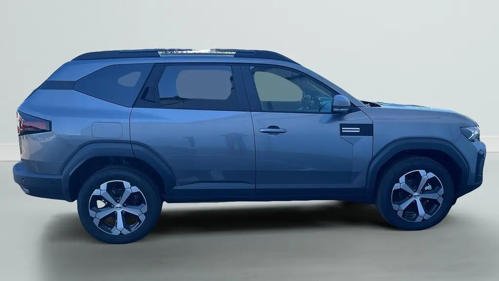Profil droit du SUV Dacia Bigster 155 Journey gris schiste avec jantes alliage 18'' et barres de toit longitudinales.