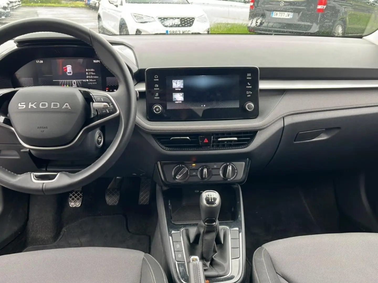 Intérieur de la Skoda Fabia 2025 vue de face, tableau de bord noir avec écran tactile et levier de vitesses manuel.